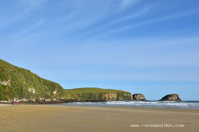 Beach, islands, windswept sky, spot of red against green